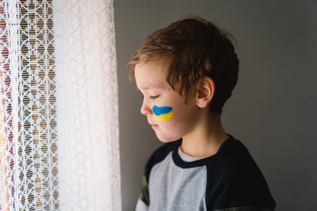 Portrait of a Ukrainian boy with a face painted with the colors of the Ukrainian flag.